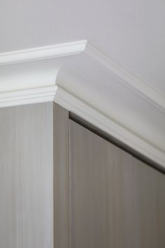 the corner of a white painted room with molding on the wall and trim around it