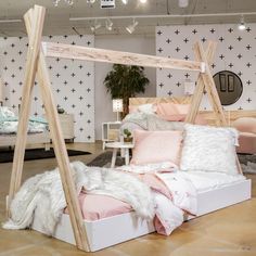 a white bed with pink pillows and blankets on it in a room that is decorated with cross - patterned wallpaper