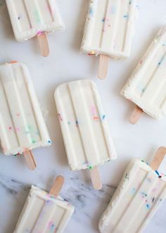 white popsicles with sprinkles on them sitting on a marble counter top