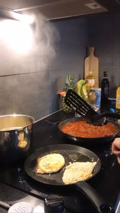 two pans with food cooking on top of a stove