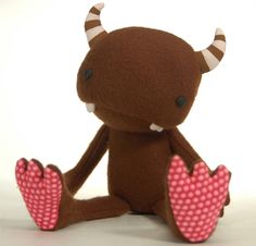 a brown stuffed animal with horns and pink polka dots on it's legs sitting in front of a white background