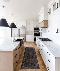 a large kitchen with white cabinets and wood flooring on the walls, along with an area rug