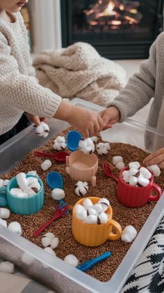 two children are playing with marshmallows in front of the fire place,