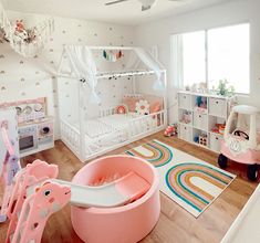 a child's bedroom decorated in pink and white with lots of toys on the floor