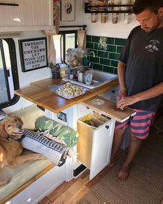 a man standing next to a brown dog in a kitchen