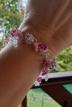 a person's hand with a pink and white beaded bracelet on their wrist