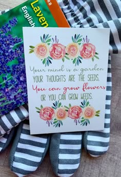 there is a card and some flowers on top of a bed with striped sheets next to it