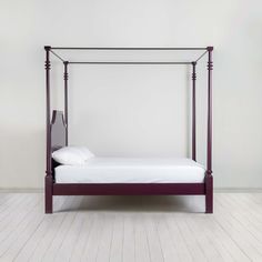 a bed that is sitting in the middle of a room with white walls and wood floors