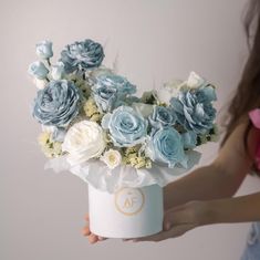 a woman holding a bouquet of blue and white flowers in her hand, with the letter af on it