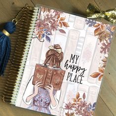 a notebook with an illustration of a woman reading a book and the words my happy place on it