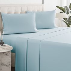 a bed with light blue sheets and pillows