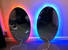 two round mirrors with colored lights on the wall in front of them, one is plugged into a charger