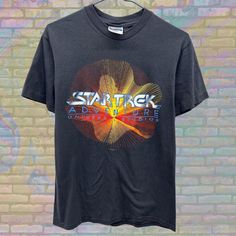 Label size: Medium Recommended size: Small How it fits: Regular Pit to pit: 18" Shoulder to bottom: 26.5" Flaws: Photos show marks if any Material : 100% Cotton Era: 80s Colour: Black/Multicolor Star Trek Gifts, Star Trek Shirt, Space Movies, Retro Space, Vintage Star, Label Sizes, Star Trek, Graphic Tee, Sci Fi