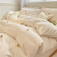 an unmade bed with white sheets and gold stars