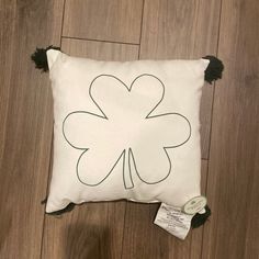 a white pillow with a four leaf clover on it and black pom - poms