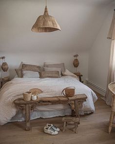 a bed sitting in a bedroom next to a wooden table and lamp hanging from the ceiling