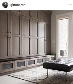 a large room with wooden cabinets and a bench in the middle, along with an area rug on the floor