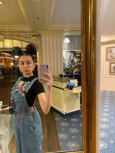 a woman taking a selfie in front of a mirror with mickey mouse ears on her head