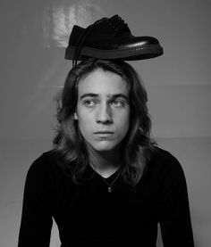 a black and white photo of a man with a shoe on top of his head