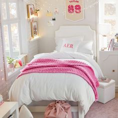 a white bed topped with a pink blanket