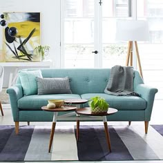 a blue couch sitting in a living room next to a table with a potted plant on it