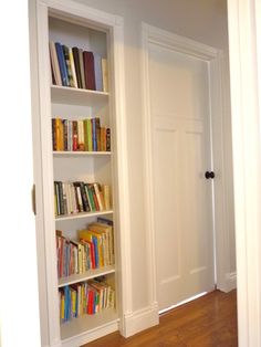 an open book shelf with books on it in a room next to a white door