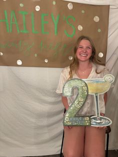 a woman holding up a sign with the number two on it and a glass in front of her