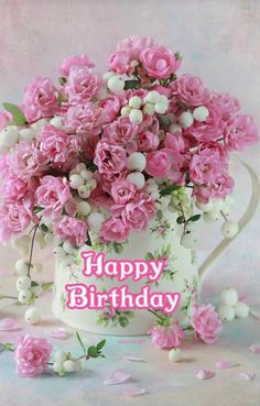 pink flowers in a white watering can with happy birthday text on the bottom right corner