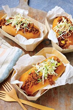 three chili dogs in paper containers with forks