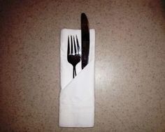 a fork and knife are sitting on a white napkin with a black stripe down the middle