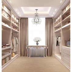 an elegant walk in closet with chandelier and dressing area, beige carpeting