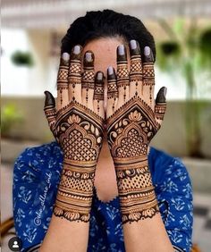 a woman holding her hands up to her face with hendi tattoos on their palms