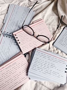 four notebooks with writing on them are laying on a bed