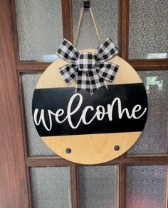 a welcome sign hanging on the front door with a bow around it's neck