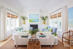 a living room filled with white furniture and lots of windows