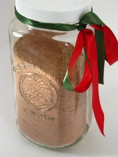 a glass jar filled with sand next to a red ribbon