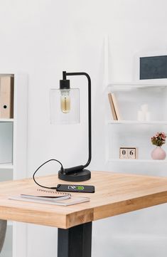 a wooden table with a lamp on top of it next to a book shelf and shelves