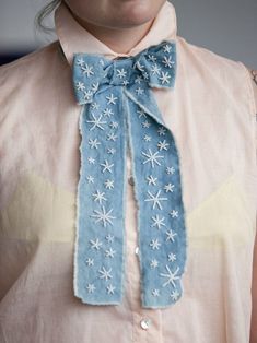 a close up of a person wearing a blue scarf with snowflakes on it