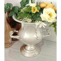 a silver vase filled with flowers on top of a table