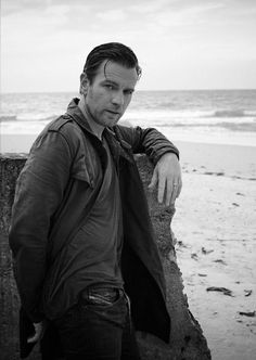 a man leaning against a wall on the beach