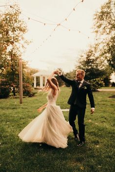 a bride and groom dancing in the grass