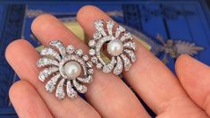 These awesome circa 1950s pierced earrings are each accented with one (1), post set, cultured saltwater Akoya pearl and thirty-nine (39), prong/bead set, old European/brilliant/single cut diamonds. The earrings measure 29.6mm X 25.7mm. The earrings are finished with hinged backs. White Gold Pearl Earrings With 17 Jewels For Wedding, Fine Jewelry Clip-on Diamond Earrings For Evening, Evening Clip-on Diamond Earrings Fine Jewelry, Exquisite Evening Earrings With 17 Jewels, Fine Jewelry Diamond Pearl Earrings For Evening, Fine Diamond Pearl Earrings For Evening, Elegant Round Clip-on Cluster Earrings, Elegant Round Cluster Clip-on Earrings, Vintage White Diamond Earrings For Formal Occasions