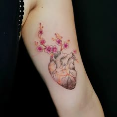 a heart shaped tattoo with pink flowers on the left side of the arm and chest