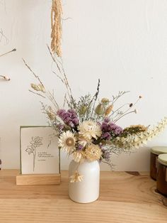 a vase filled with flowers sitting on top of a wooden table next to two cards