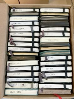 a box filled with lots of books sitting on top of a table next to a red ribbon