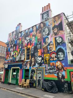 a multi - colored building with many pictures painted on it's side and scaffolding around the corner