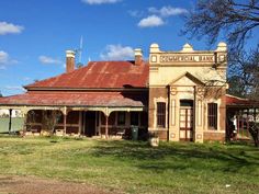 an old brick building sitting on top of a lush green field under a blue sky