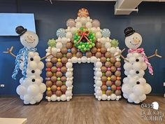 three snowmen are standing in front of an arch made out of balloons