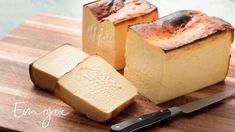 two pieces of bread sitting on top of a wooden cutting board next to a knife