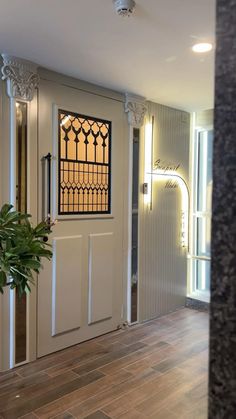 an entry way with a potted plant on the floor and two doors to another room